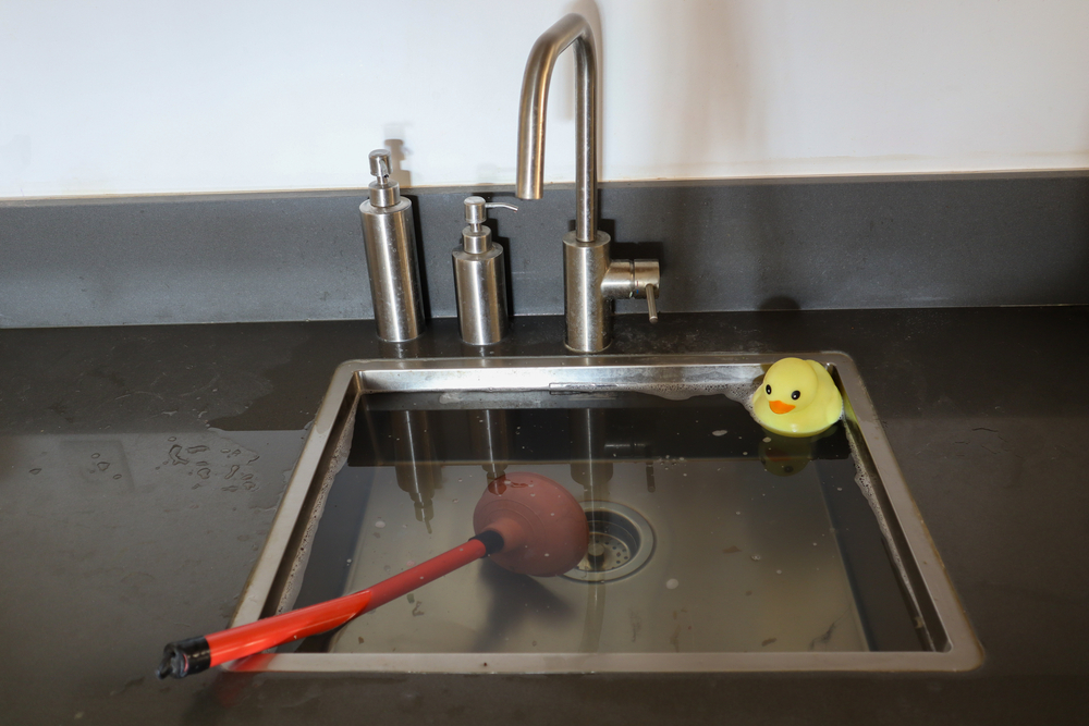 Overflowing,kitchen,sink,,clogged,drain.,plunger,(force,cup),and,yellow