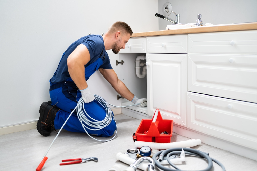 Male,plumber,cleaning,clogged,sink,pipe,in,kitchen