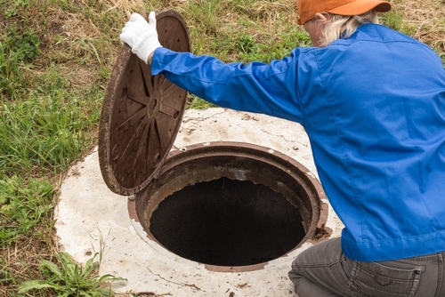A,working,plumber,opens,a,sewer,hatch.,maintenance,of,septic