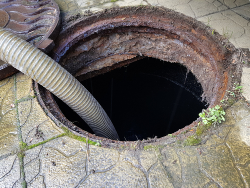 A,hose,is,lowered,into,the,sewer,manhole,to,pump