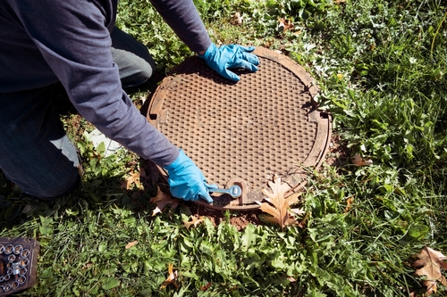 A,working,plumber,opening,septic,system,tank.,copy,space,for